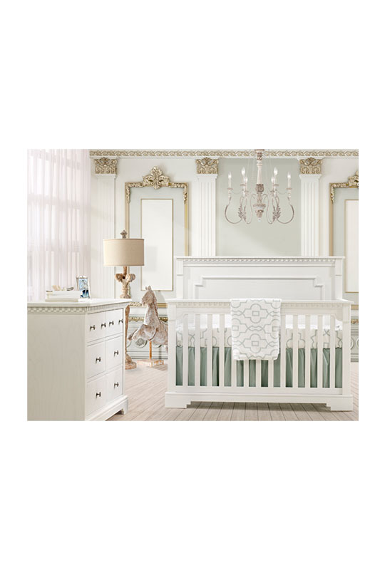 White and gold baby room with white classic double dresser and crib with detailed moldings