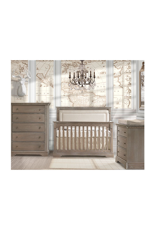 Baby room with world map wallpaper, wooden crib with beige upholstered panel, 3 drawer dresser and 5 drawer dresser