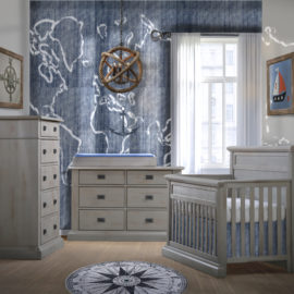 Baby room with blue naval wall and decor, with grey chalet crib, double dresser and 5 drawer dresser with black metallic handles