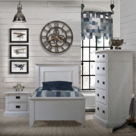 White Bedroom with wood panelled walls, blue curtain and sheets with white wooden twin bed, two drawer nightstand, and 5 drawer dresser with black metallic handles