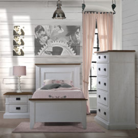 Bedroom with wood panelled walls, pink curtain and sheets with white wooden twin bed, two drawer nightstand, and 5 drawer dresser with black metallic handles