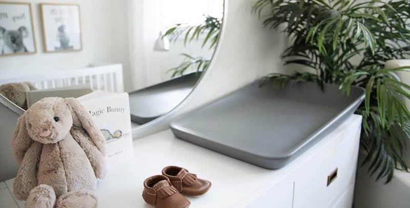 Nursery dresser with grey changing mat, round mirror and bunny teddy bear