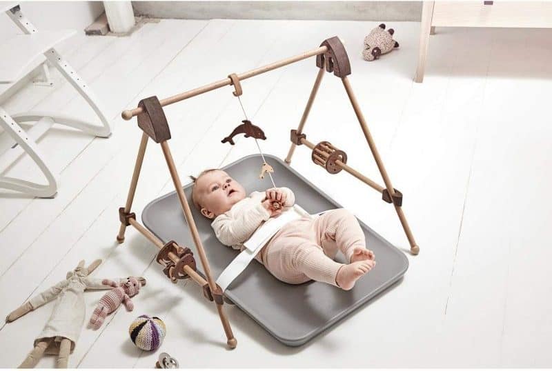 baby lying down on gray changing mat with toys